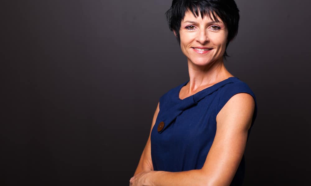 confident middle aged woman with black hair and blue dress