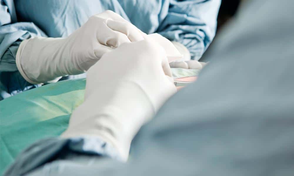 surgeons in operating room with white gloves and scalpel making an incision