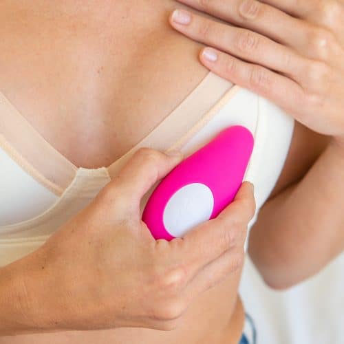 woman uses the pink lavie breast massager over bra