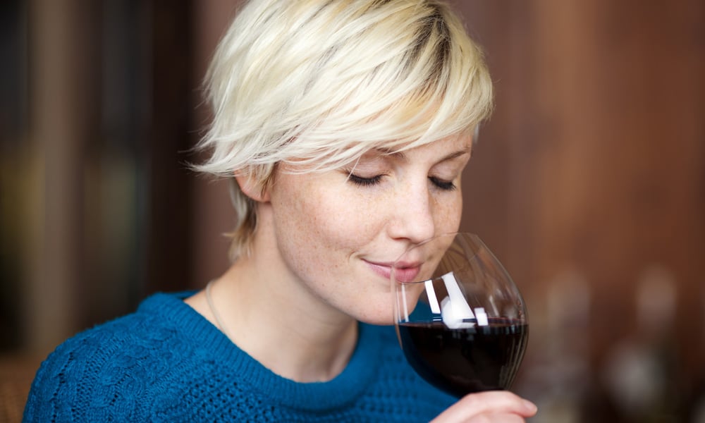 woman enjoying the smell of red wine