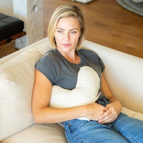 woman using a billow heart pillow under her arm for comfort