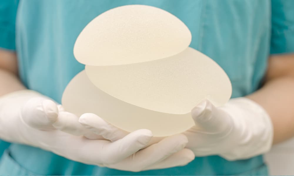 textured breast implant held by surgeon in scrubs