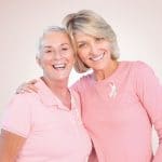 middle aged women dressed in pink hugging each other