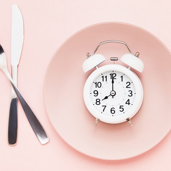 fasting alarm clock on pink plate with utensils