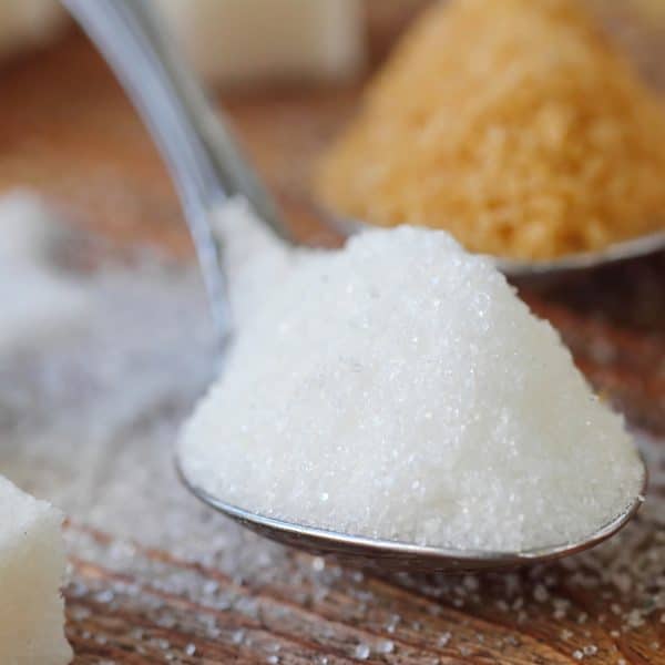 white sugar on a spoon next to brown sugar